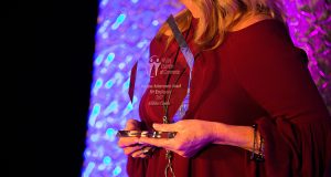 Woman holding 2017 Business Achievement Award.