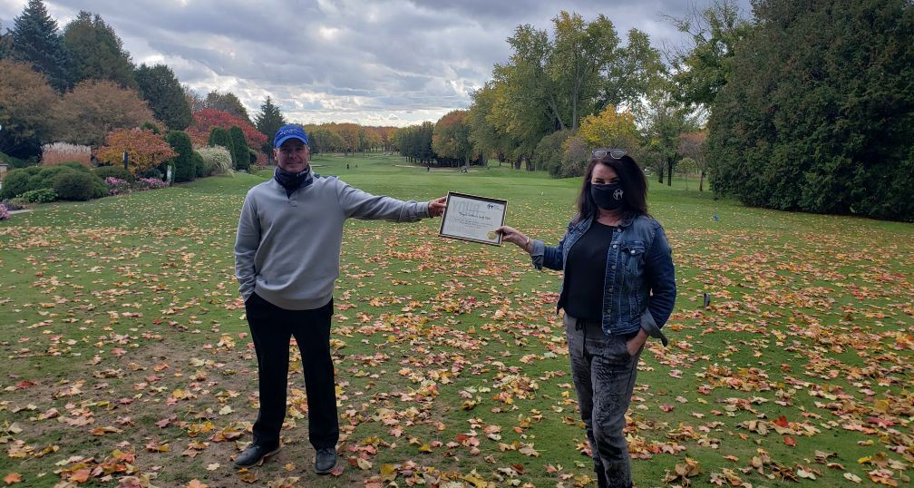 Lorna McGhee presents Dave Paterson a certificate outside on the greens of Royal Ashburn Golf Course